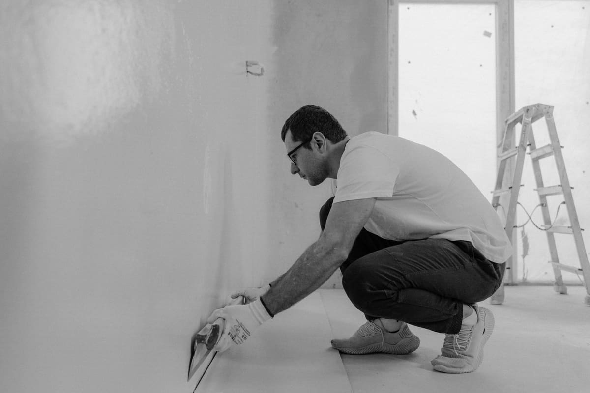 Artisan carreleur posant du carrelage grand format dans une douche italienne