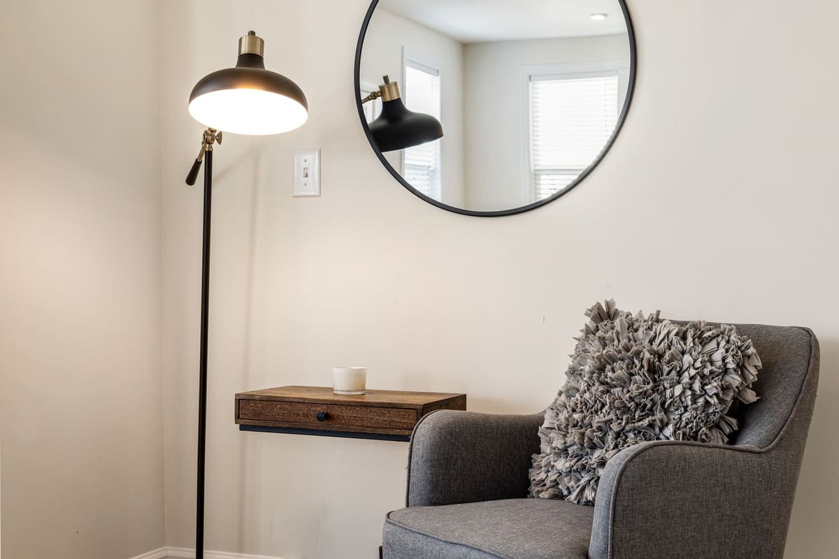 Lampadaire liseuse à bras articulé positionné près d'un fauteuil de lecture